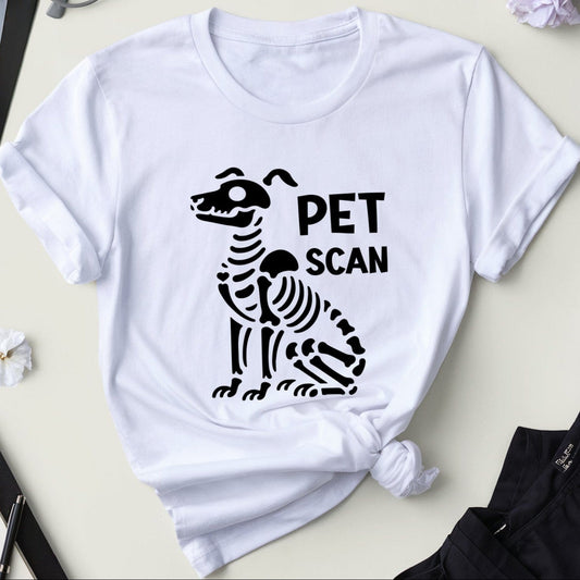 White t-shirt with black zebra skeleton design and 'PET SCAN' text on a light surface with medical-themed items.