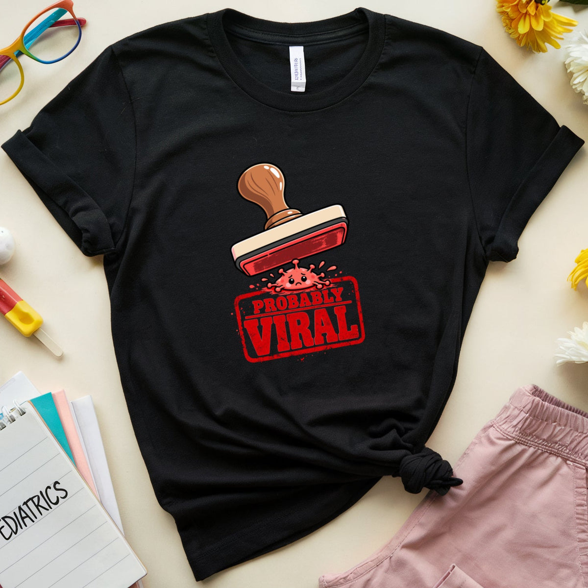 A black graphic t-shirt with a red and brown stamp design that reads 'PROBABLY VIRAL' in a flat-lay arrangement on a beige background, surrounded by pink shorts, colorful glasses, flowers, and notebooks.
