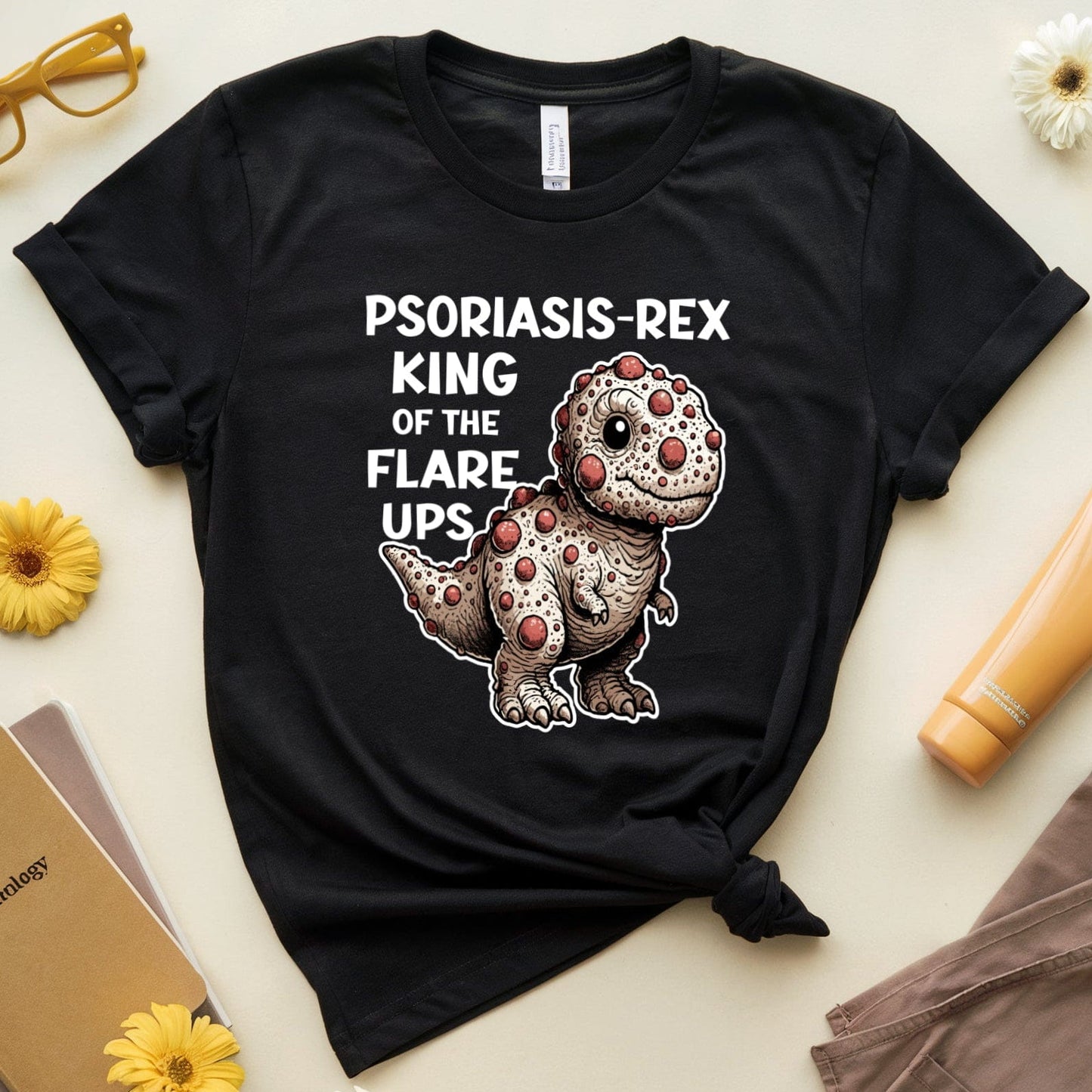 Black t-shirt with a dinosaur graphic and text on a light surface with accessories.