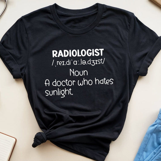Black t-shirt with 'RADILOGIST' definition text on a light surface with medical-themed items.
