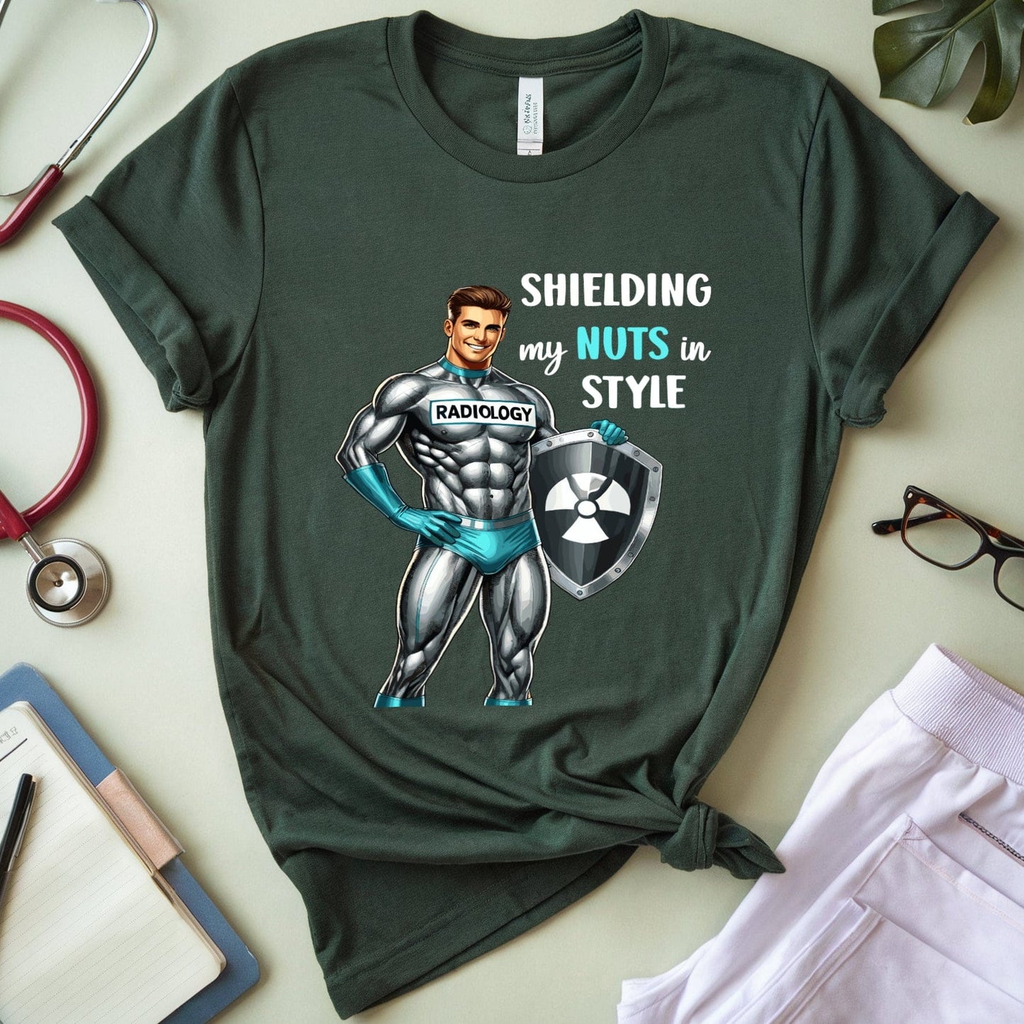 Green t-shirt with superhero graphic and text on a light surface with medical-themed items.