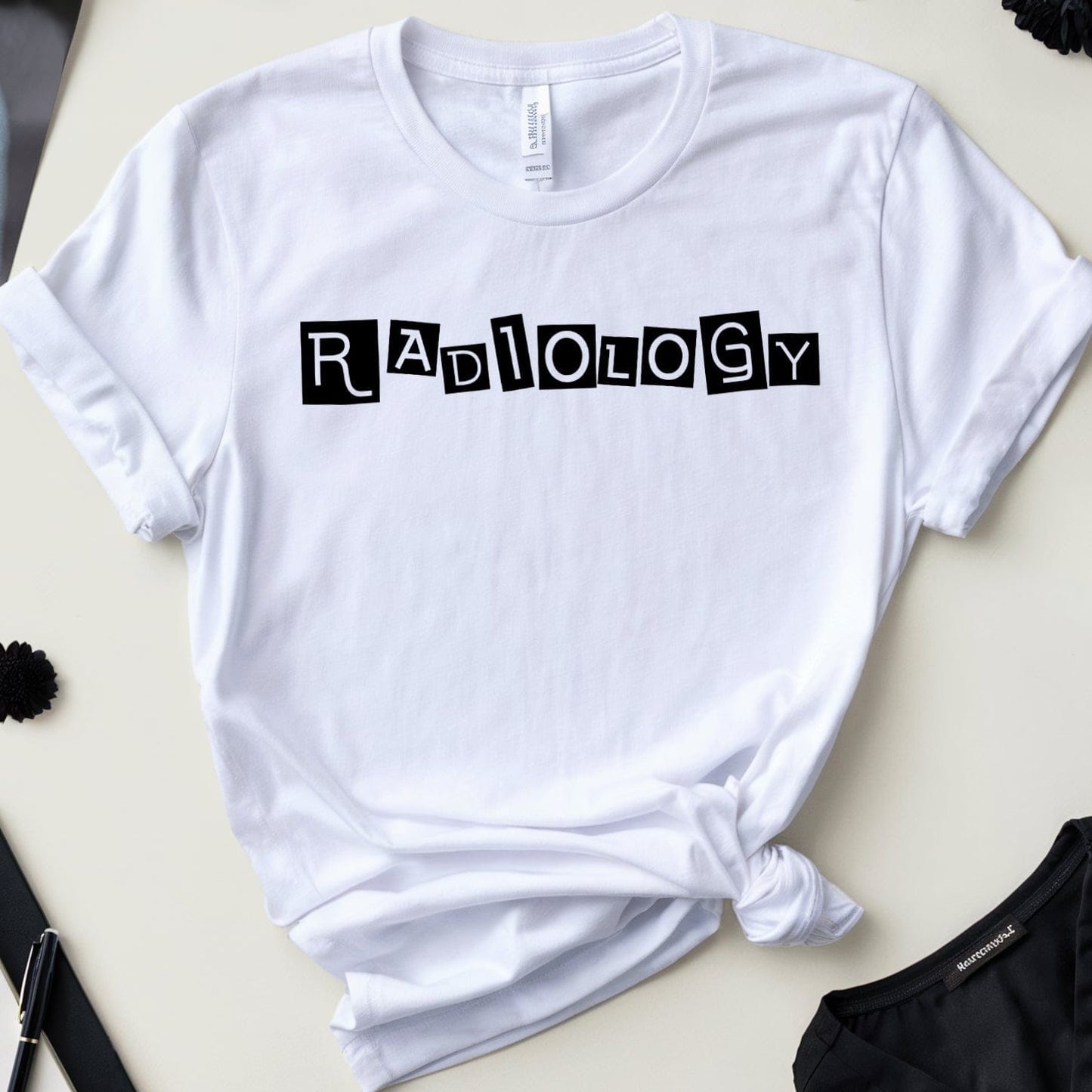 White t-shirt with 'Radiology' text on a desk with medical-themed items.
