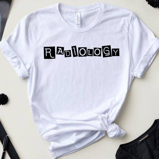 White t-shirt with 'Radiology' text on a desk with medical-themed items.