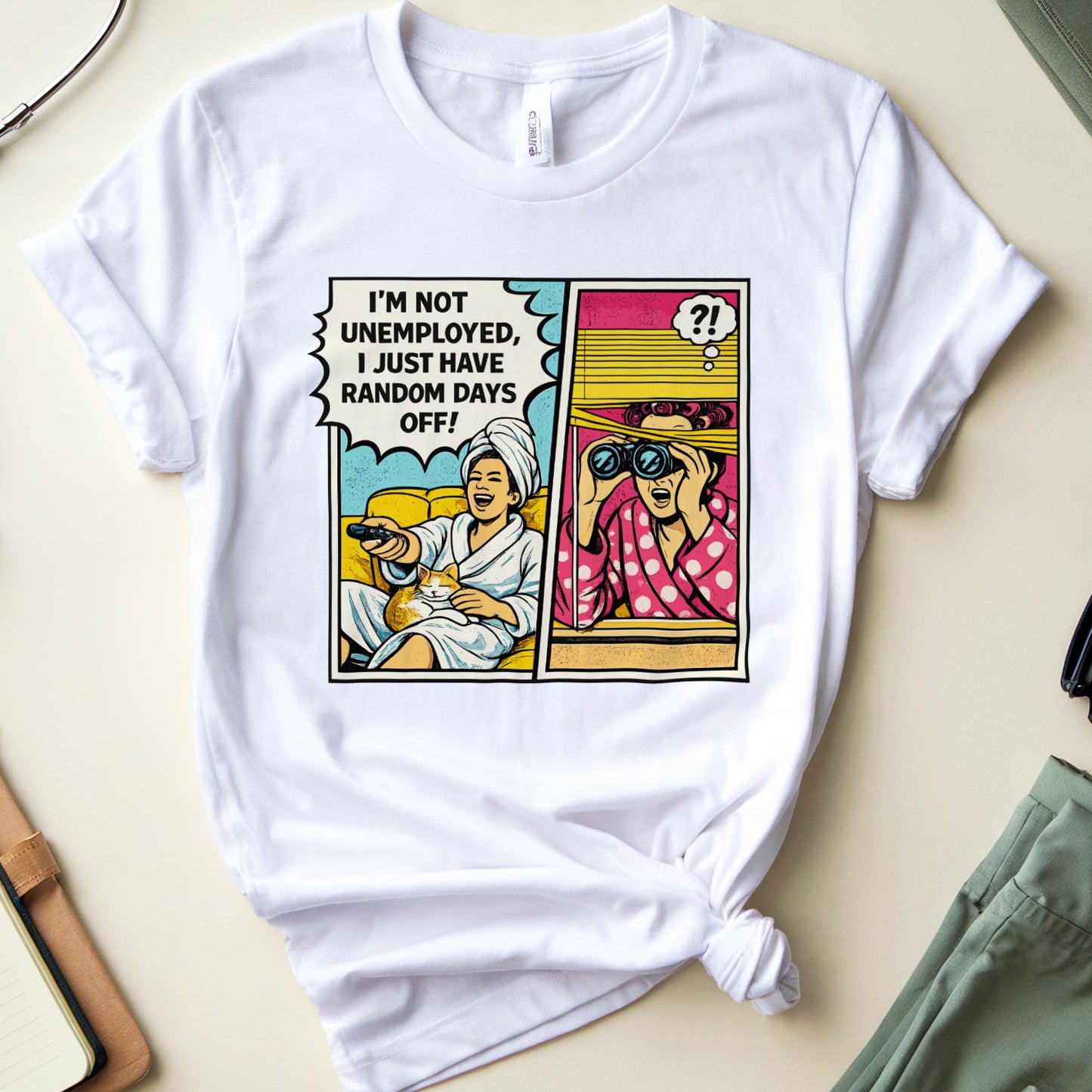 White t-shirt with a graphic design on a light surface with medical and casual items.