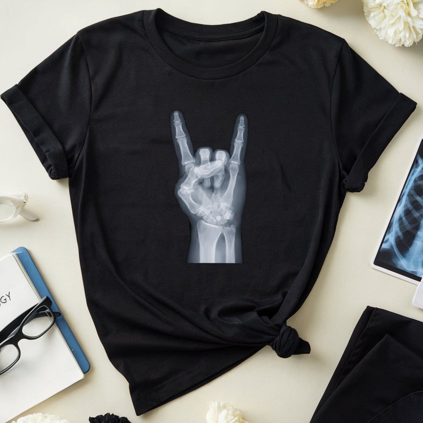 Black t-shirt with hand gesture design on a light surface with flowers and medical books.