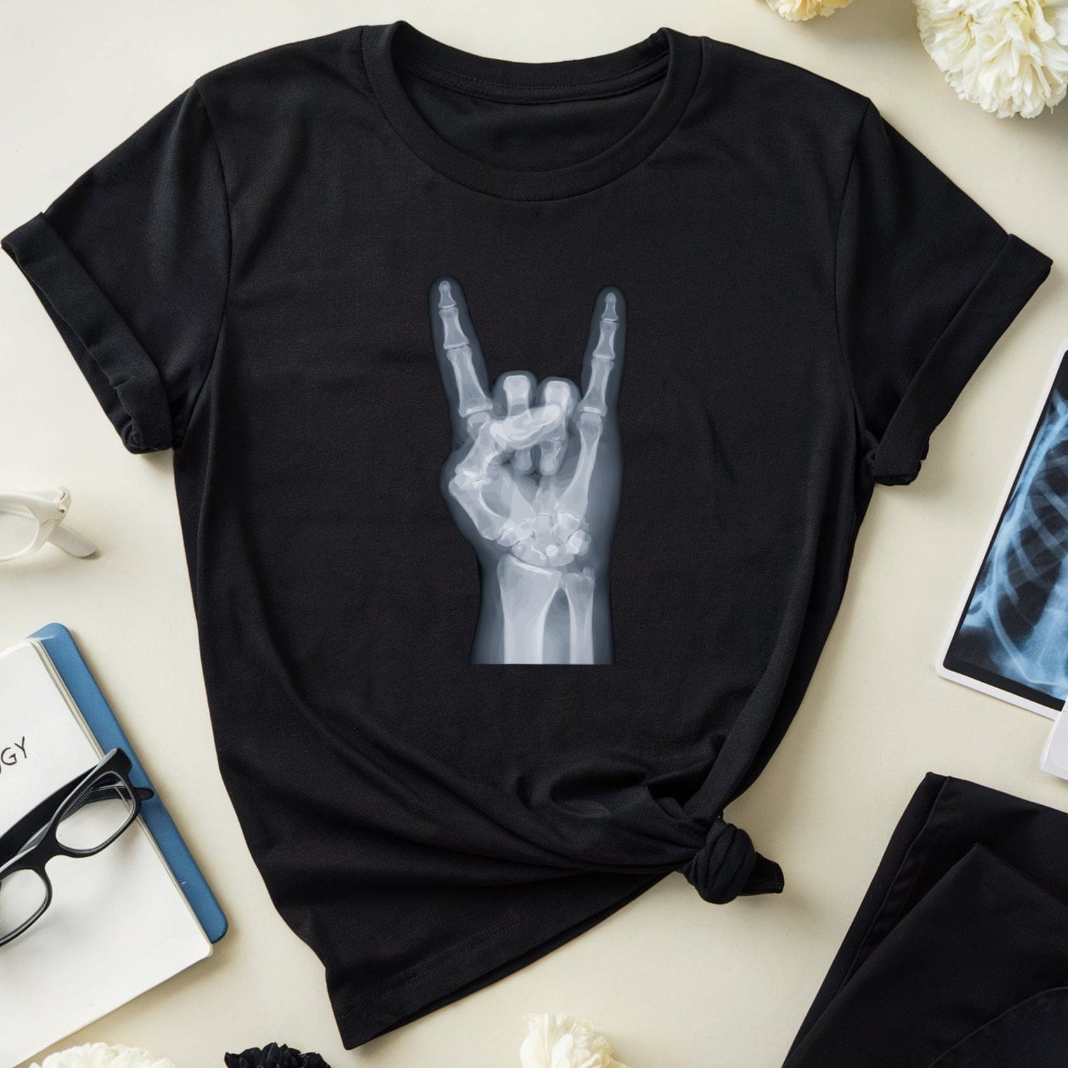 Black t-shirt with hand gesture design on a light surface with flowers and medical books.