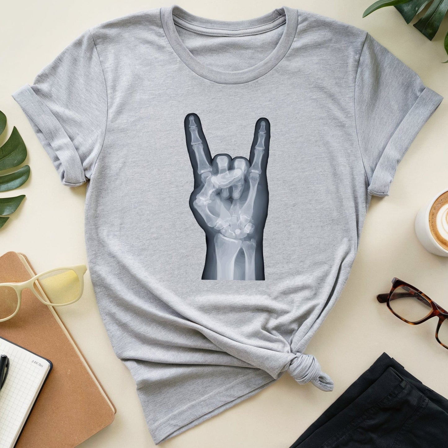 Gray t-shirt with a hand gesture design on a table with accessories