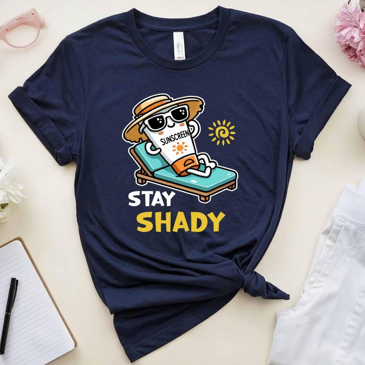 Navy blue t-shirt with a graphic design and text 'Stay Shady' on a light surface with accessories.