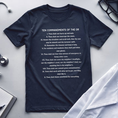 Navy blue t-shirt with 'Ten Commandments of the OR' text on a white surface with medical equipment.