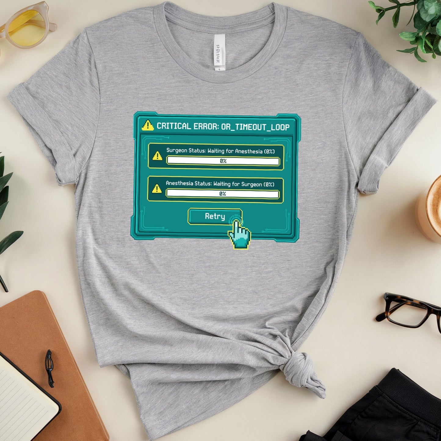 Gray t-shirt with a graphic design on a table with accessories