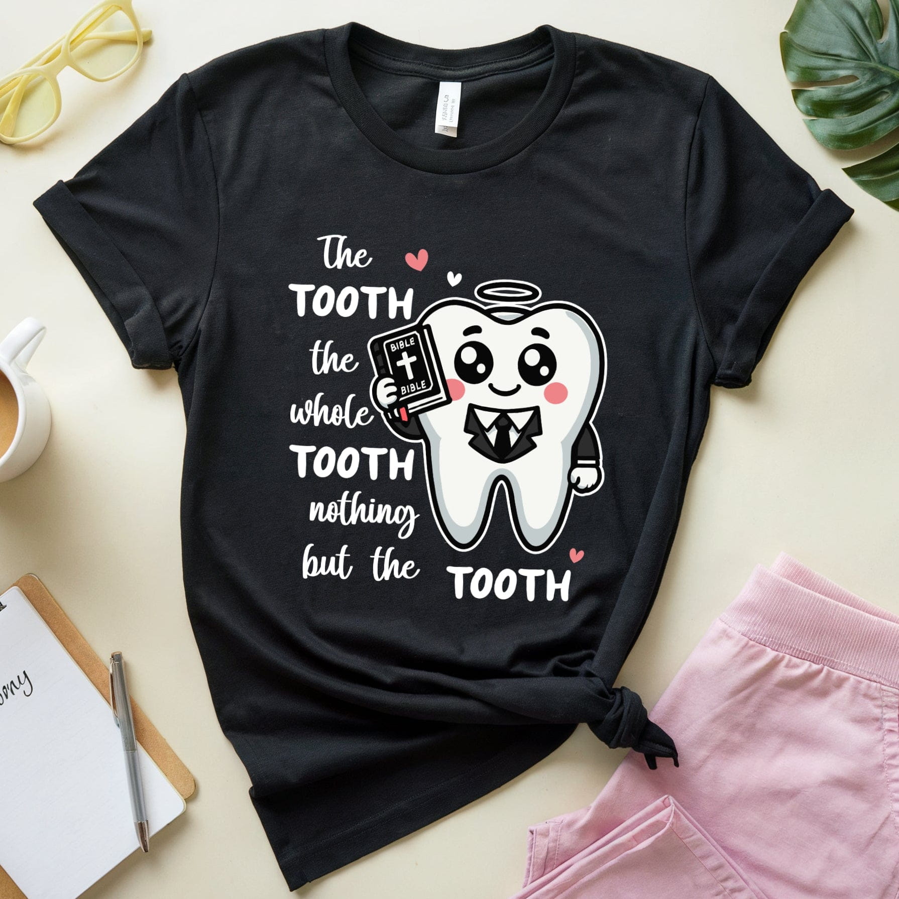 Black t-shirt with a tooth graphic and text on a light surface with accessories.