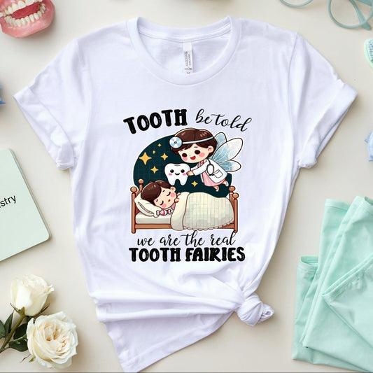 White t-shirt with cartoon design and text on a table with flowers and dental-themed items.