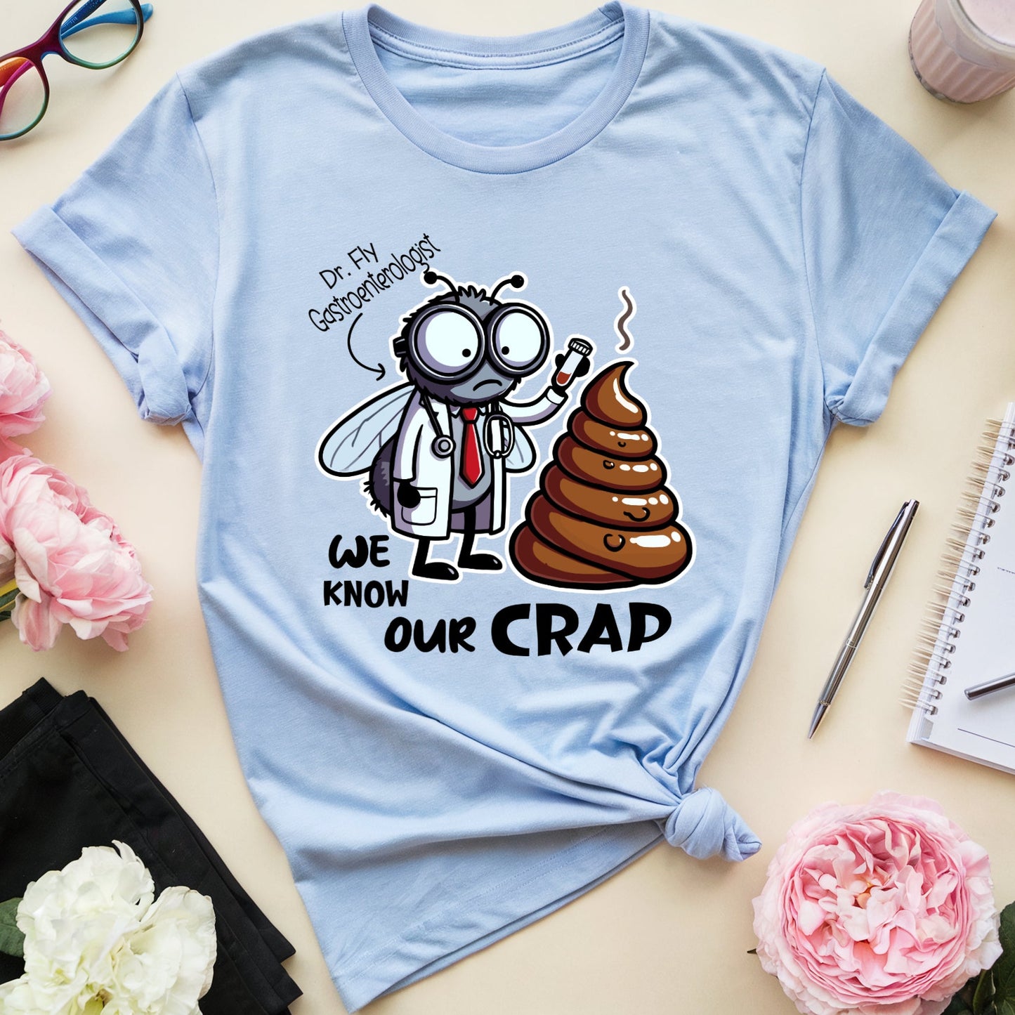 Light blue t-shirt with a funny graphic design of a dr fly a gastroenterologist holding a test tube near a huge pile of poop.