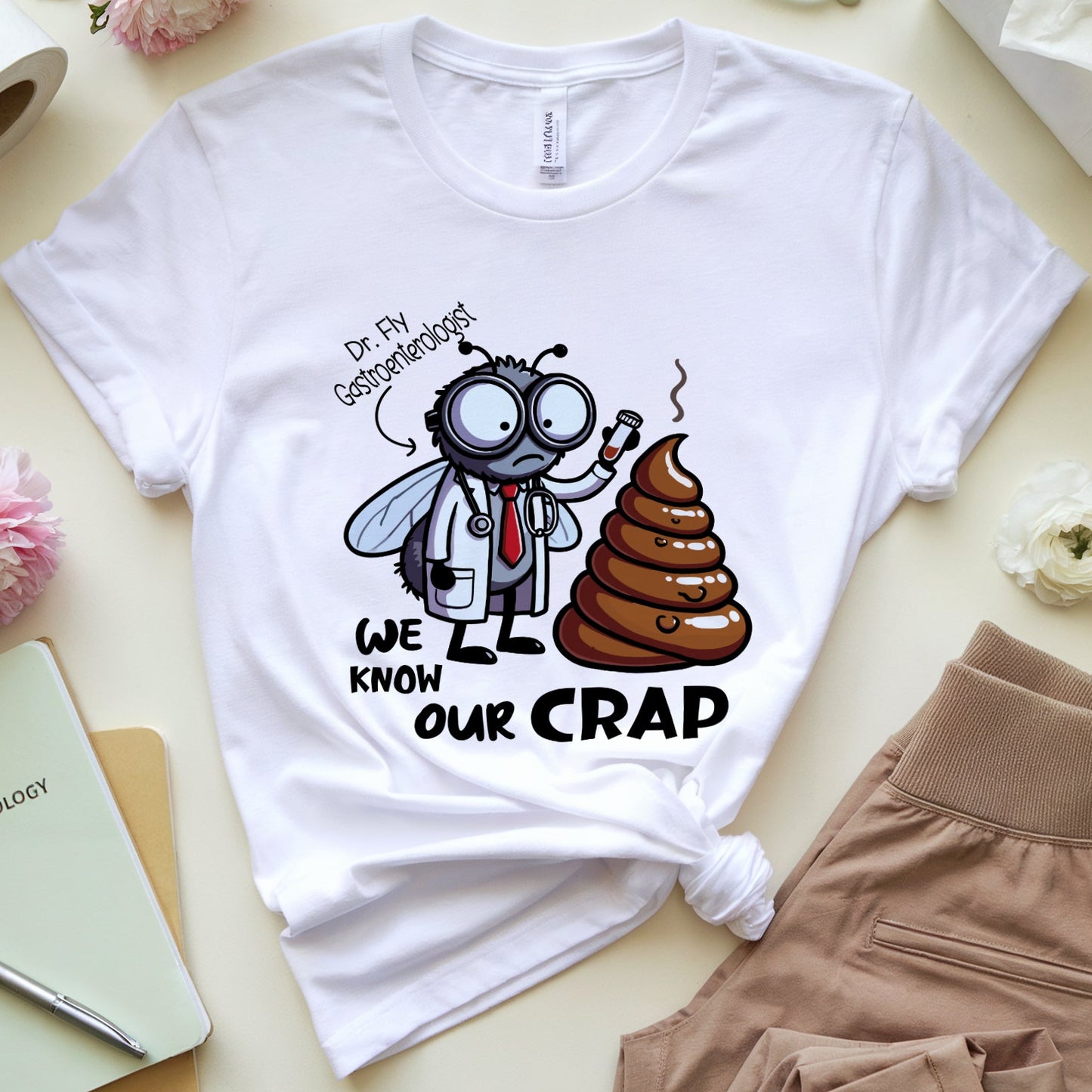 White t-shirt with a a funny graphic design of a dr fly a gastroenterologist holding a test tube near a huge pile of poop.