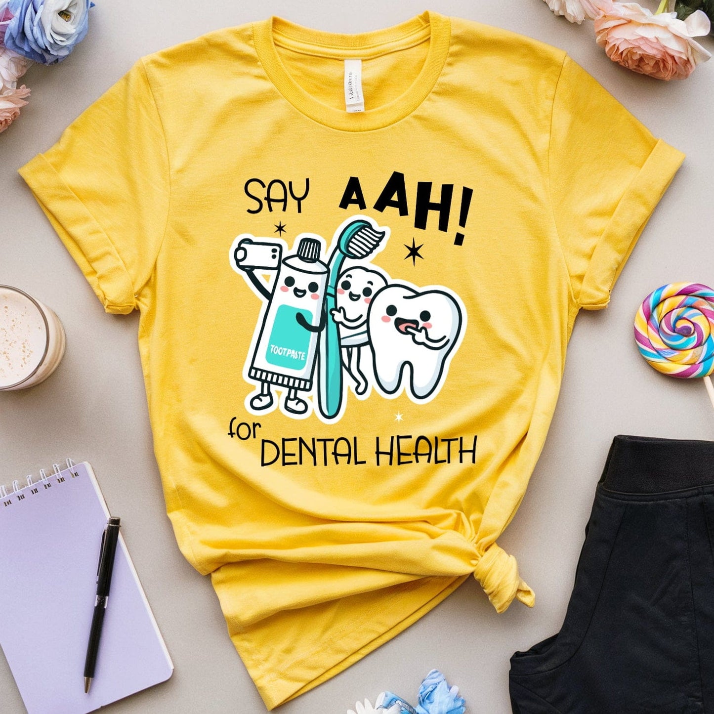 Yellow t-shirt with dental-themed design on a light surface with accessories.