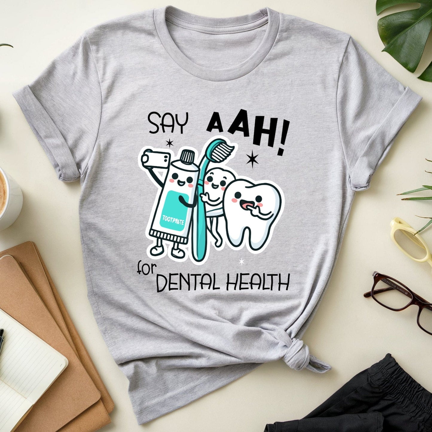 Gray t-shirt with dental-themed design on a light surface with office items.