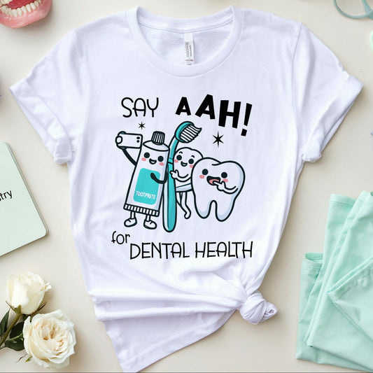 White t-shirt with dental-themed design on a table with dental-themed items.
